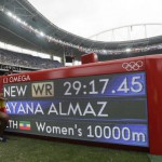 Ethiopia's Almaz Ayana poses next to a scoreboard showing her new world record in the women's 10,000-meter final during the Summer Olympics in Rio de Janeiro, Brazil, Friday, Aug. 12, 2016. (AP Photo/Matt Slocum)
