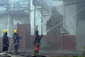 Firefighters train their hoses to contain the fire that broke out from a factory in Pacheco St., Valenzuela City on Sunday. The fire reached Task Force Bravo alarm level. (JAY GANZON)
