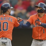 Houston Astros' Yuli Gurriel congratulates Carlos Correa after Correa hit a three-run home run in the eighth inning during Game 3 of a baseball American League Division Series against the Cleveland Indians, Monday, Oct. 8, 2018, in Cleveland. (AP Photo/David Dermer)