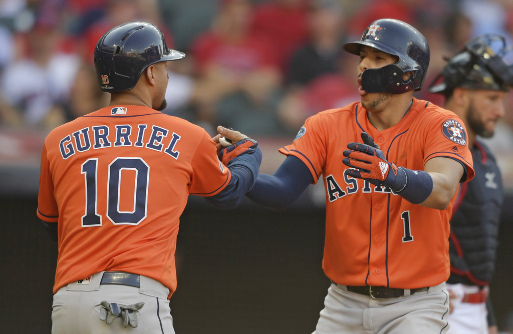 Houston Astros' Yuli Gurriel congratulates Carlos Correa after Correa hit a three-run home run in the eighth inning during Game 3 of a baseball American League Division Series against the Cleveland Indians, Monday, Oct. 8, 2018, in Cleveland. (AP Photo/David Dermer)